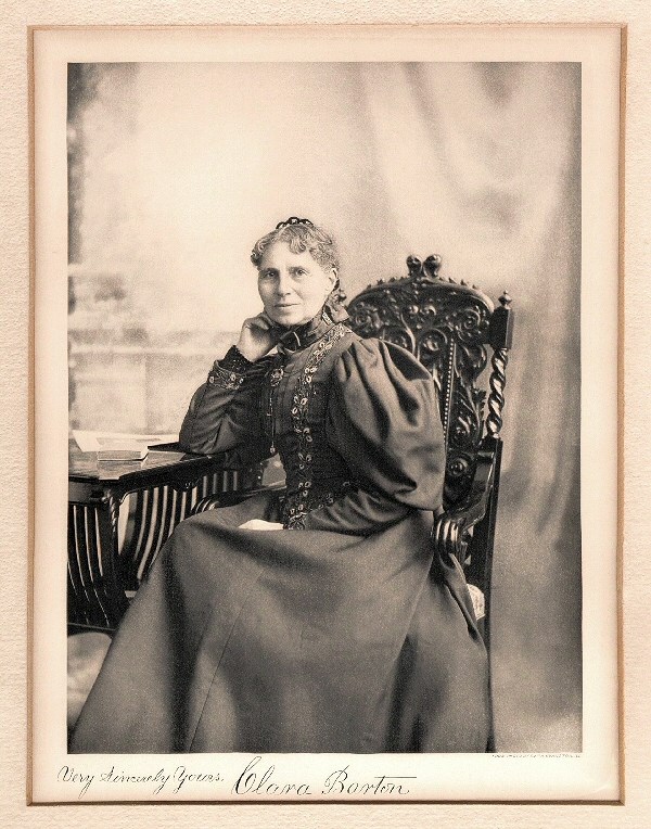 Clara Barton seated at her desk, looking at the camera