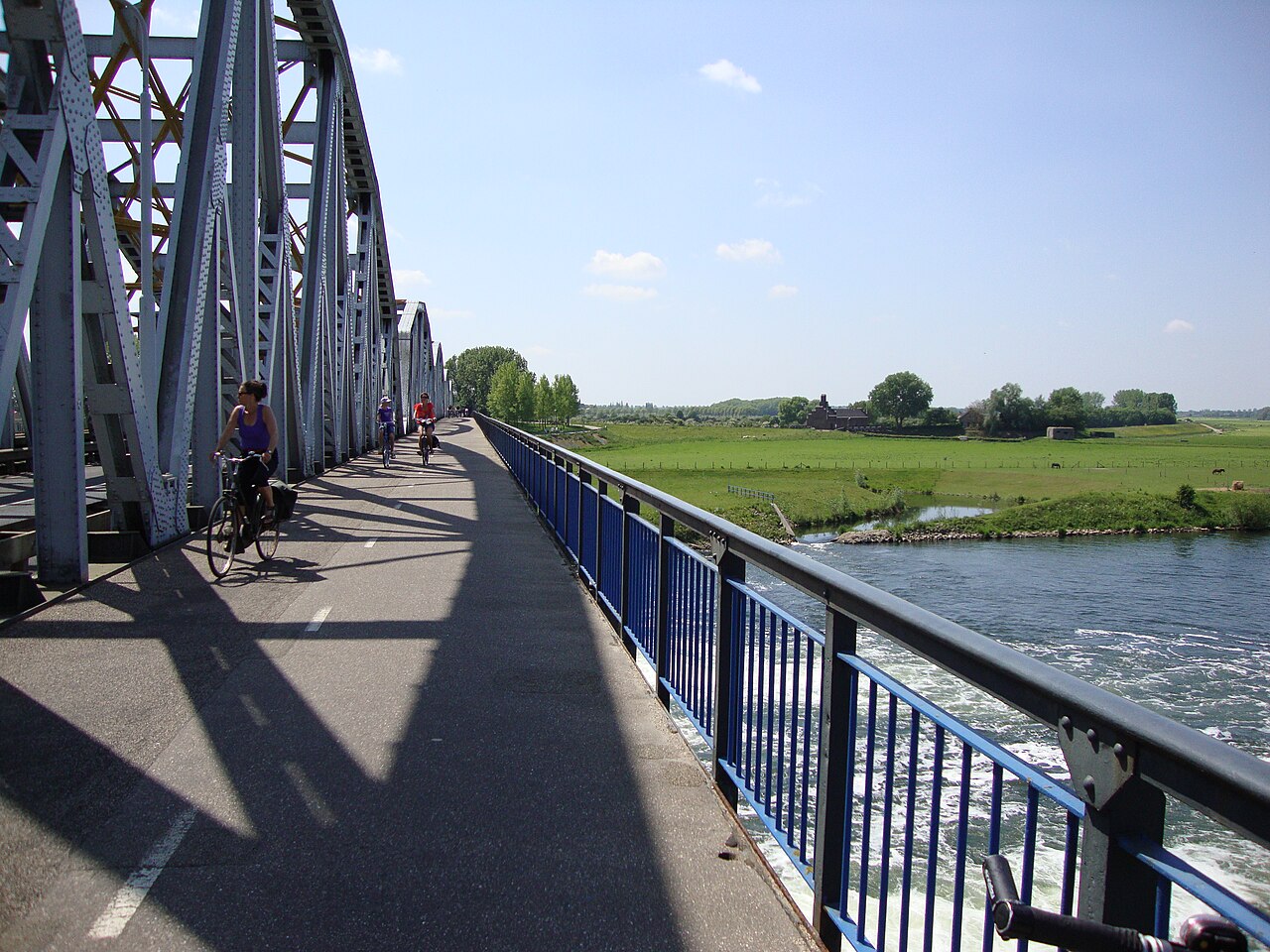 Cyclists crossing a river using a bicycle bridge