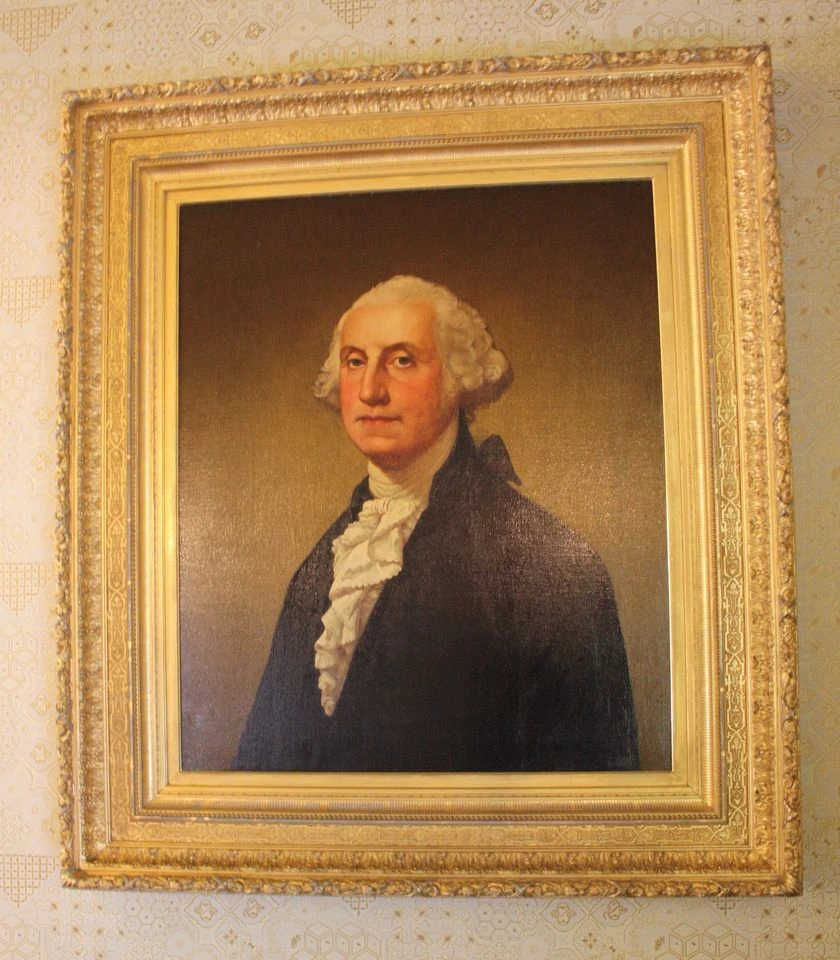 Portrait of George Washington in a black coat and white jabot, in a gilded frame