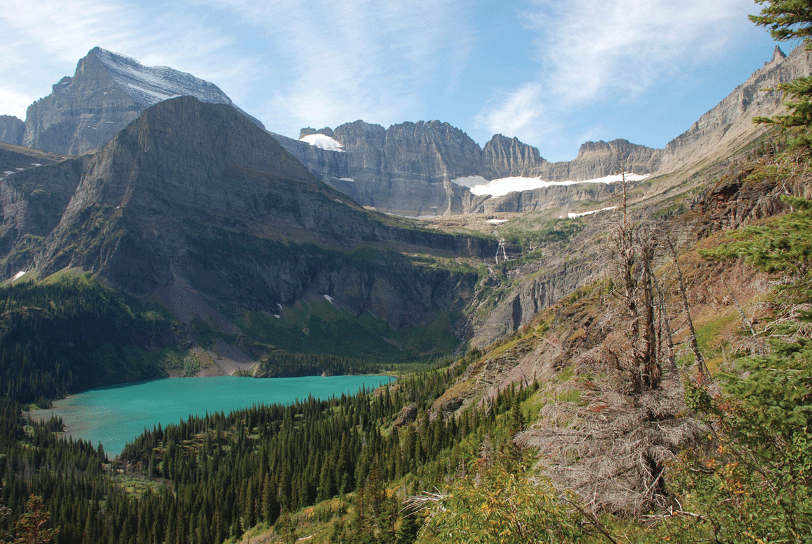 Photograph of Grinnell Glacier: a mostly rocky surface with little snow and ice, and a stream of water below.