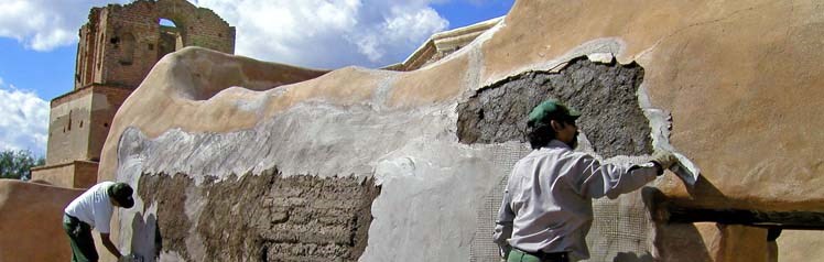 People working on the adobe wall of a Spanish mission