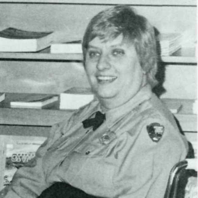 A park aide in a wheelchair wearing a long-sleeved Park Service uniform shirt and cross tie.