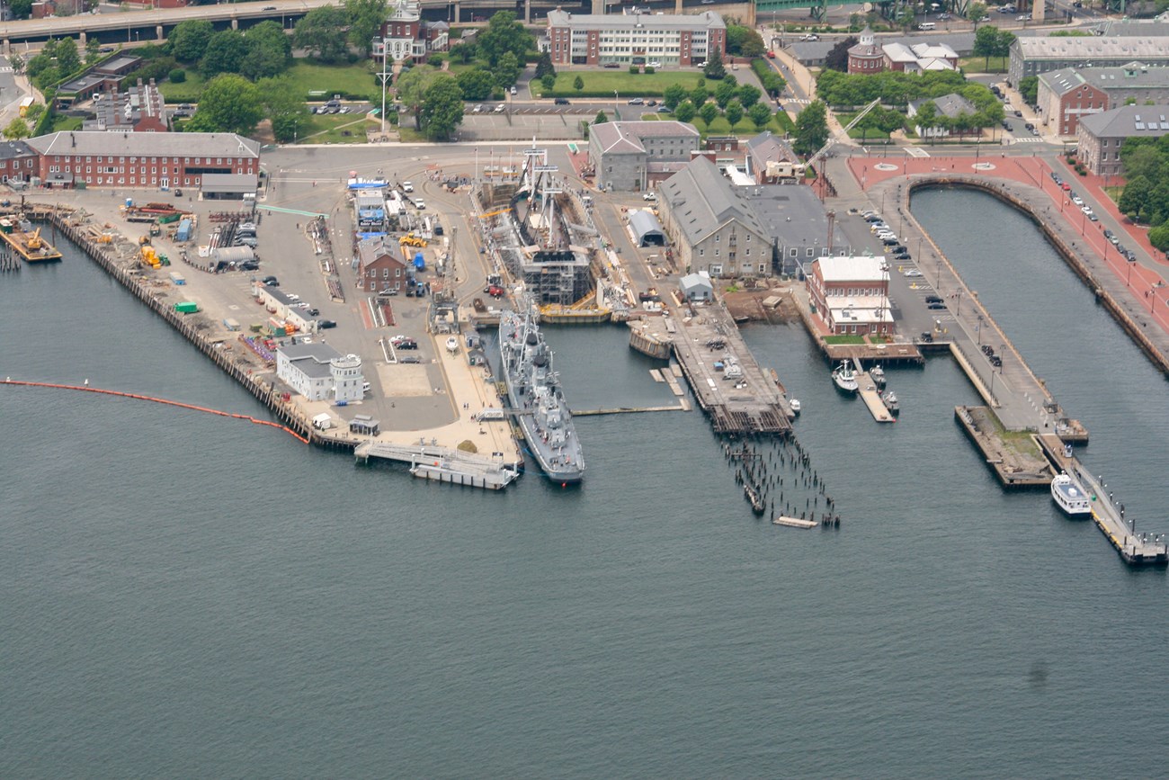 Aerial photograph of the Charlestown Navy Yard today, with the destroyer USS Cassin Young at a pier.