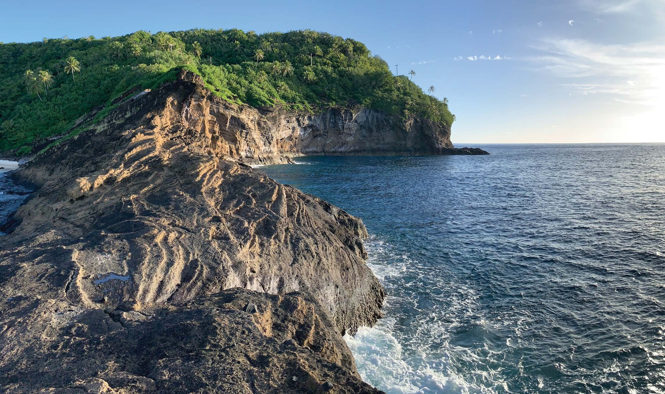 A rocky volcanic headland with layered rock meeting the ocean