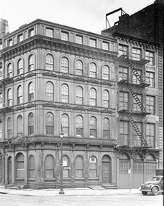 A five-story cast-iron building with arched windows and a fire escape.