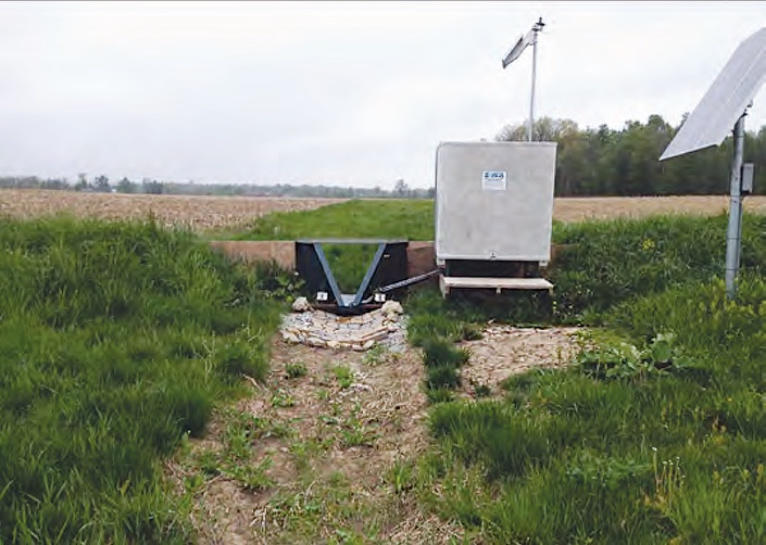 A small flume and instrument shelter at the edge of a plowed field