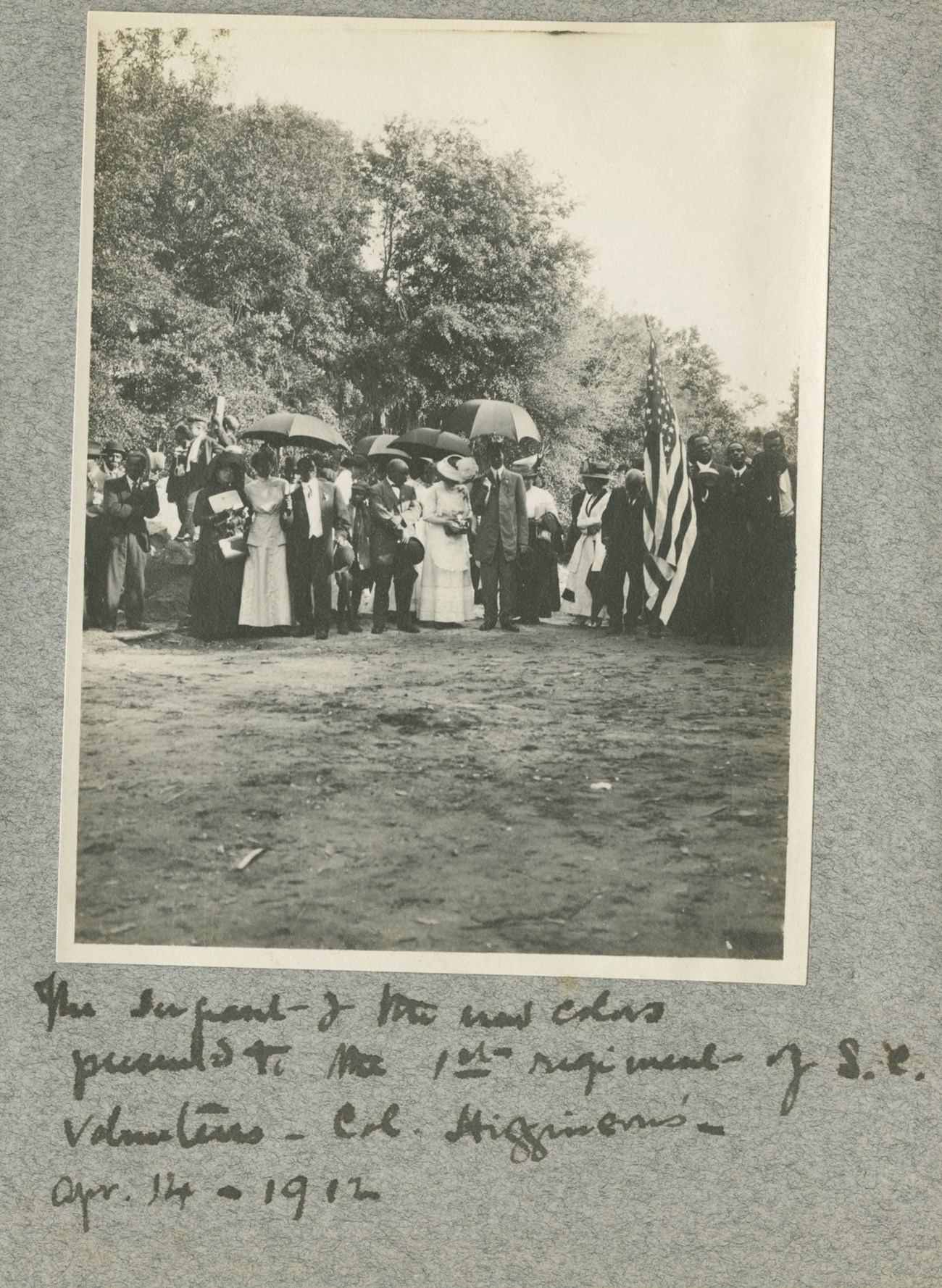 A scrapbook page with a photograph of a group of 1st South Carolina Volunteers veterans with a flag, 1912.