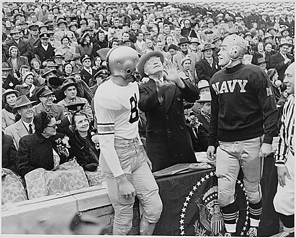 Photograph of President Truman tossing a coin in the air before the annual Army-Navy football game in Philadelphia, as the captains of the Army and Navy teams watch, 12/02/1950, ARC 200250