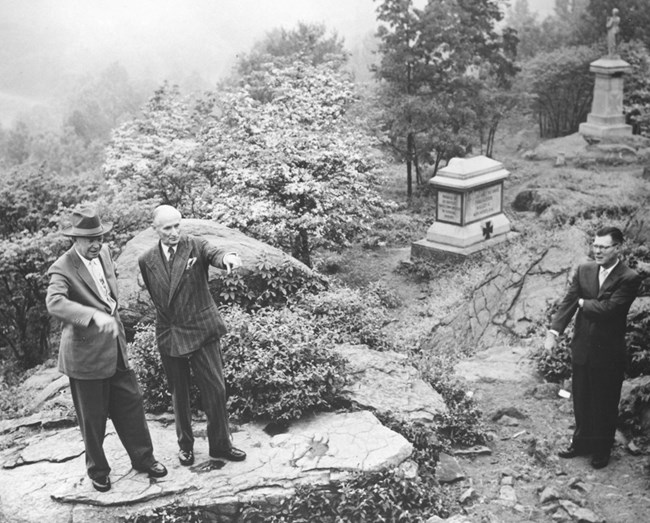 Black-and-white photo of Eisenhower and Montgomery standing on a rock and pointing.
