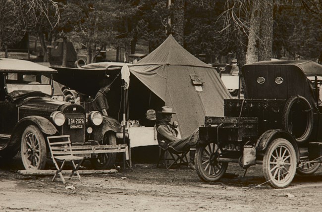 Two old cars in front of a campsite in a national park.