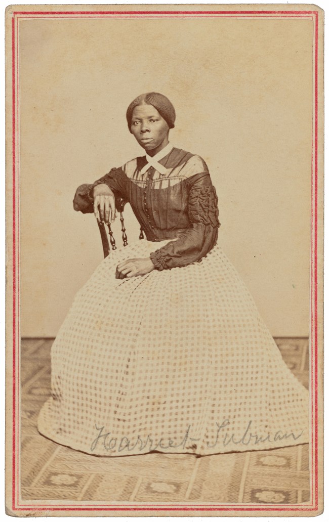 Black-and-white photograph of Harriet Tubman seated in a chair, in a full-length dress.