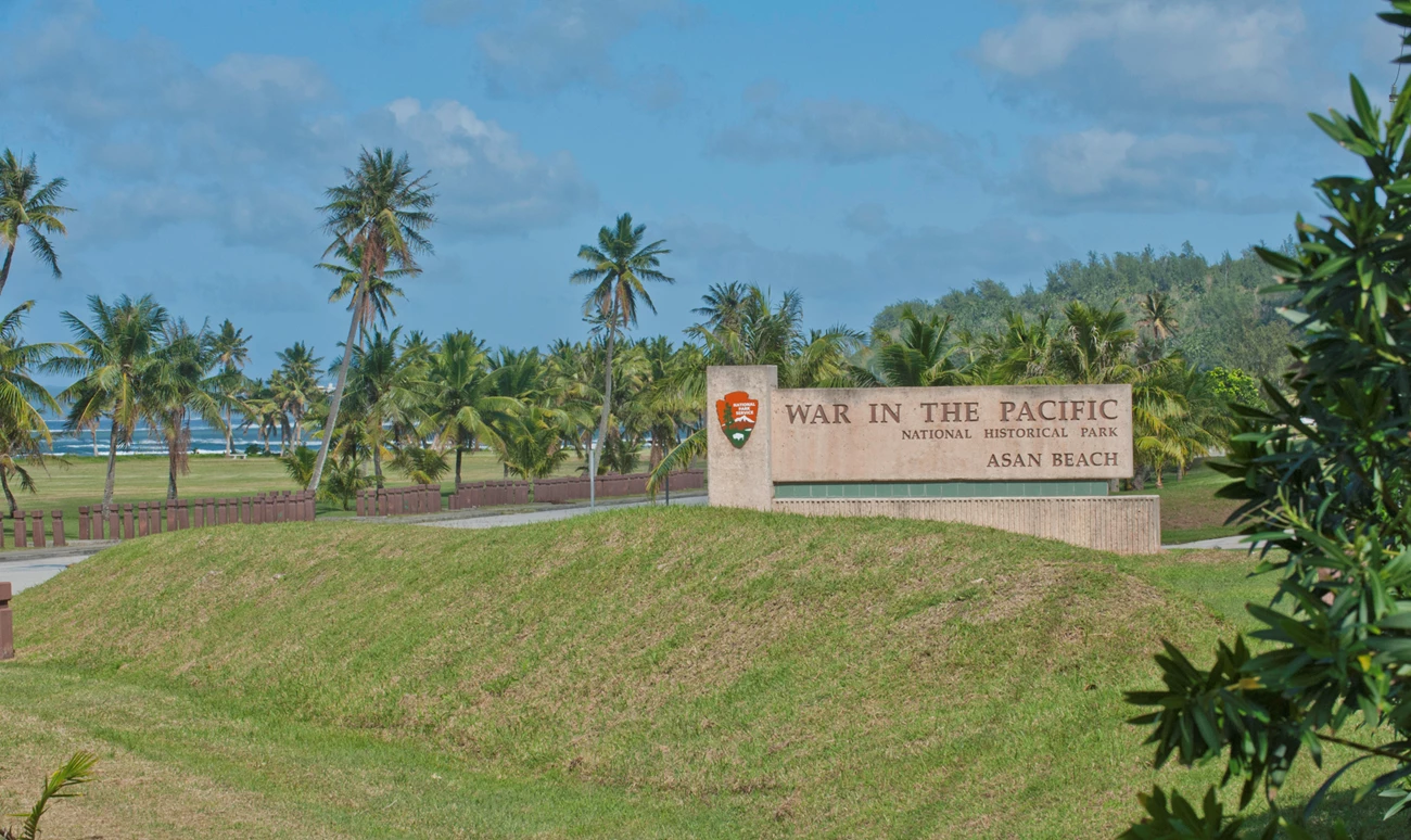 The War in the Pacific National Historical Park welcome sign behind a grassy hill.