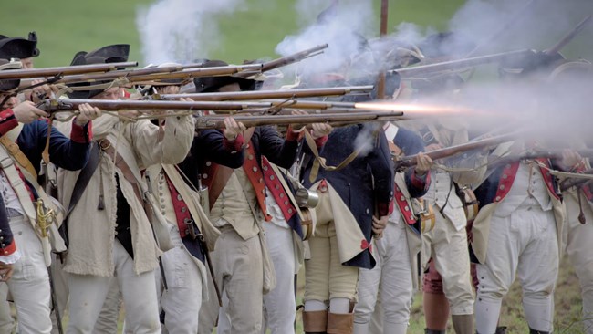 Soldiers firing muskets in a salute.