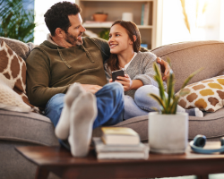 father and daughter talking on couch, daugther is holding her cellphone