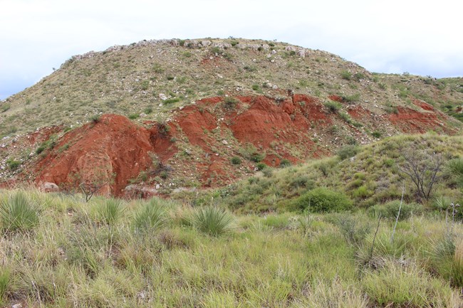 Red rock layer exposed in a hillslope beneath the Alibates Dolomite.