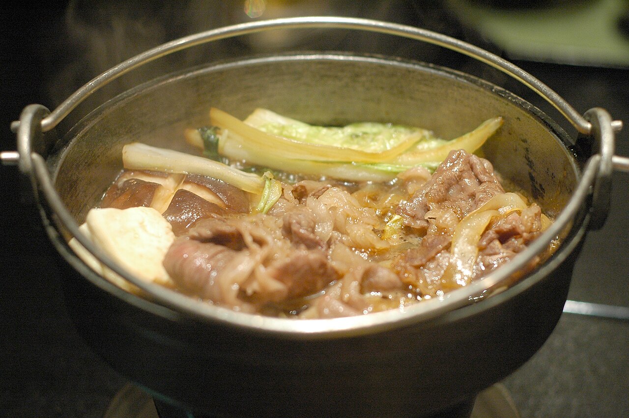A pot of sukiyaki with beef, tofu and vegetables