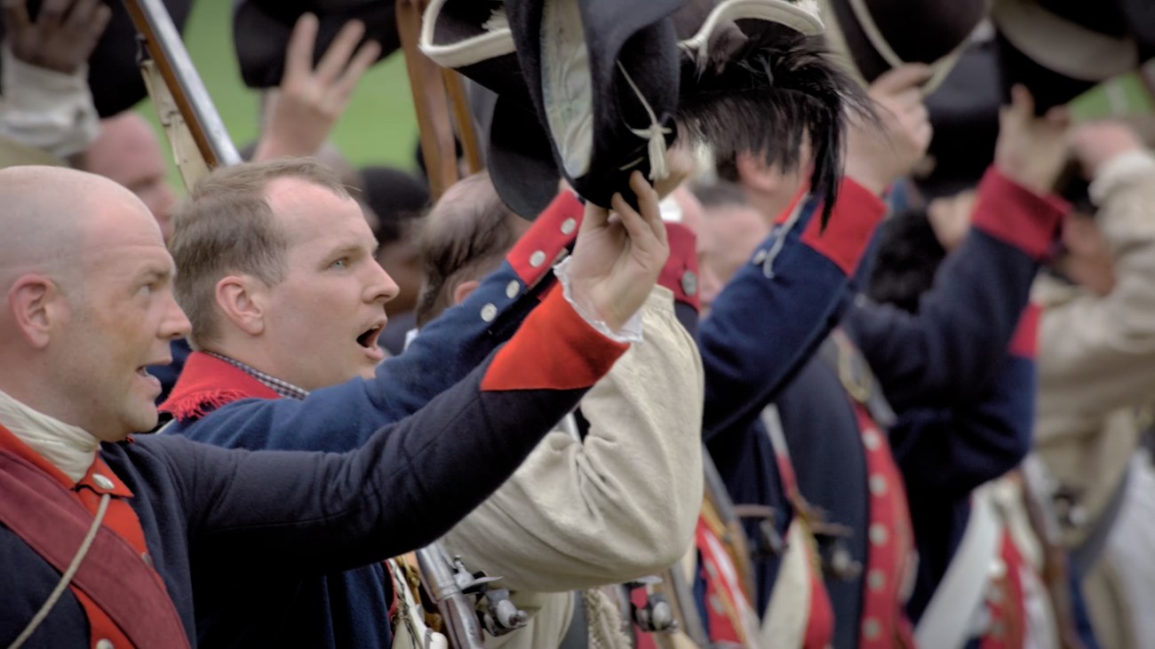 Continental soldiers cheering outdoors.
