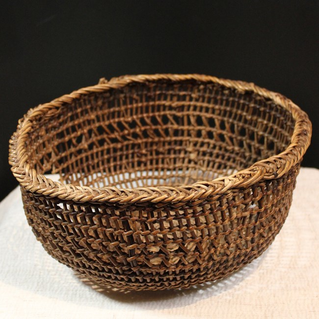 A round, open-weave basket of braided roots.