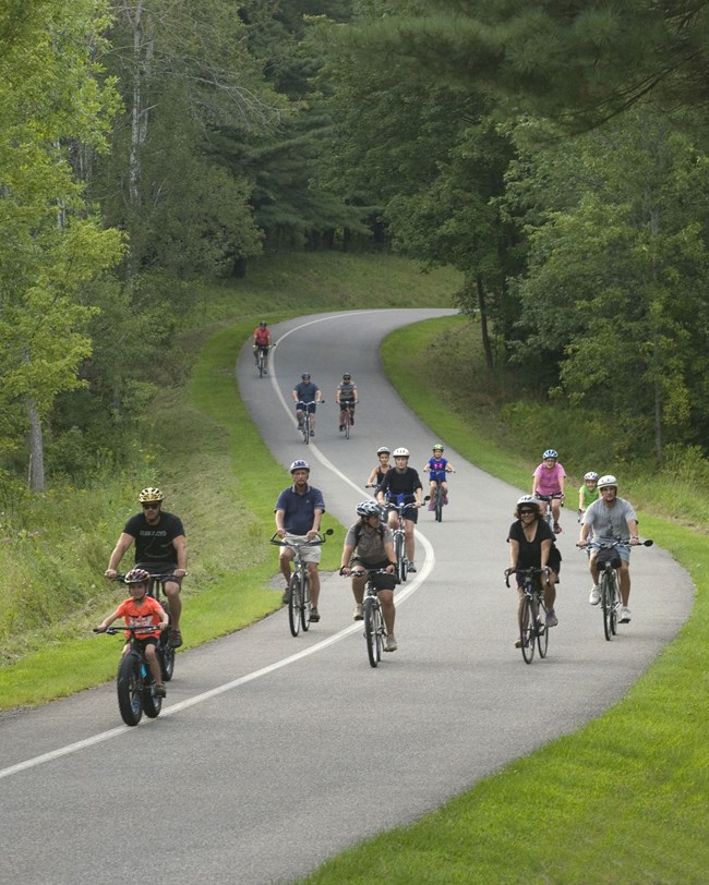 Cyclists on a paved path through rolling ground.