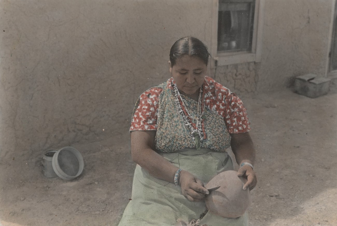 Legoria Tafoya scraping an unfired pot with a knife.