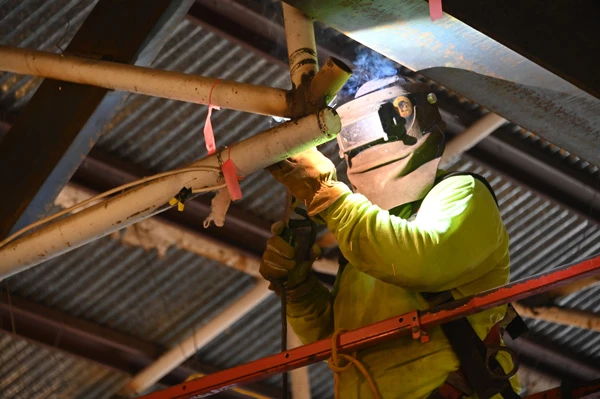 A bright glow illuminates a welder in helmet and gloves.