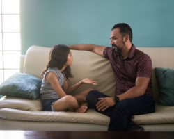 father and daughter talking on a couch