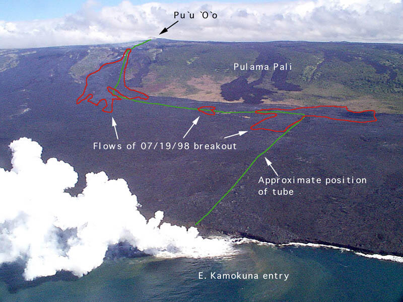 An aerial photo of fresh dark lava flows spreading across a slope toward the coast