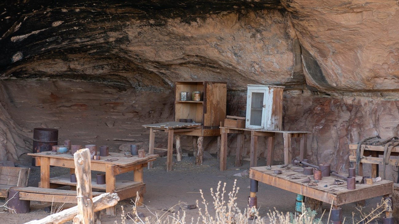 Old wooden tables and gear under a deep rock overhang