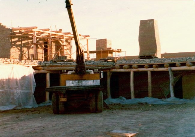 A truck beside an adobe-walled structure under construction.