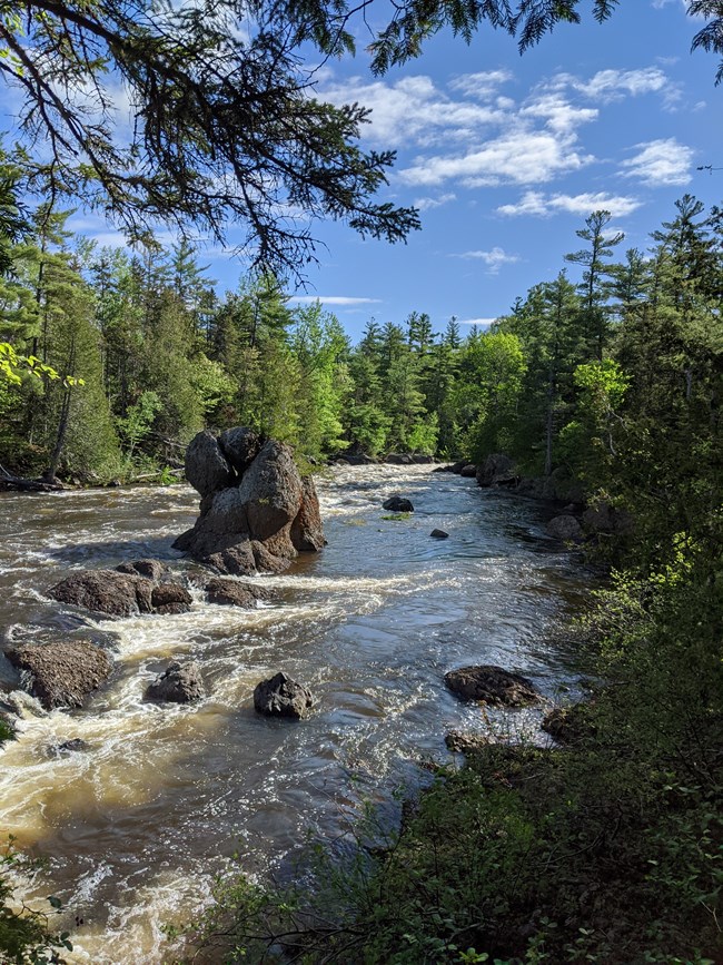 Photo of a river with rocks and a large boulder exposed