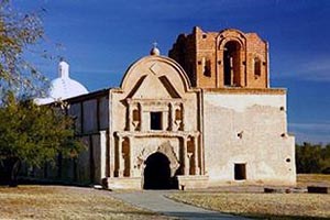 The white-plastered facade and brick bell tower of the Spanish colonial mission church of San José de Tumacácori under a blue sky
