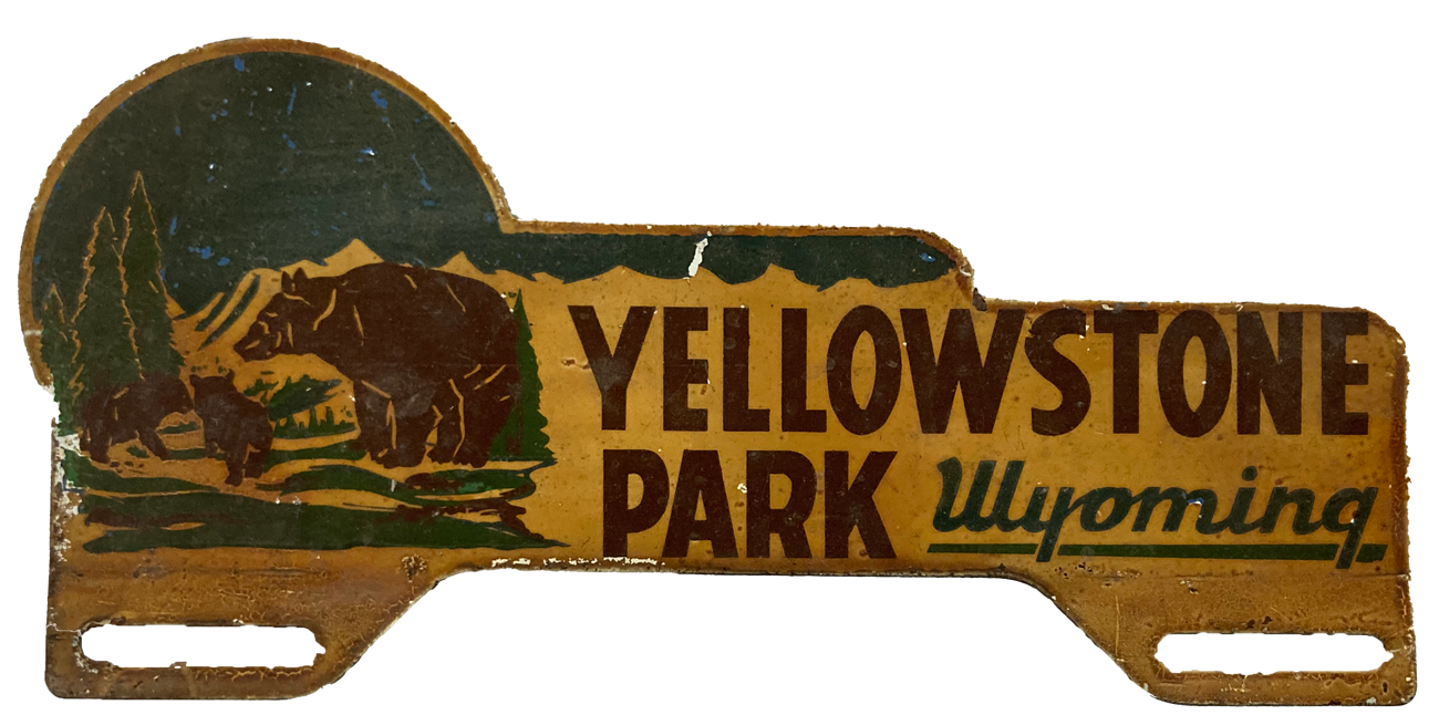 An enameled metal topper with a bear scene reading Yellowstone Park, Wyoming.