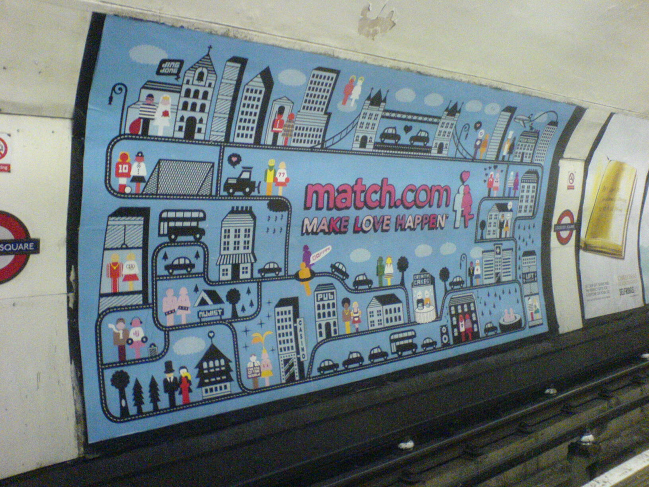 There is a large Match dot com advertisement painted on a subway wall. It shows a cartoon city filled with couples. The caption reads, make love happen.